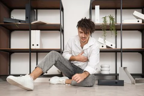 Young businessman having panic attack on floor in office Stock Photos