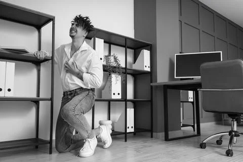 Young businessman having panic attack near shelf unit in office Stock Photos