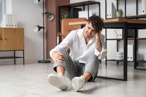 Young businessman having panic attack on floor in office Stock Photos