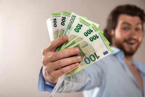 Young businessman hold 100 euro cash money banknotes isolated on a gray backg Stock Photos