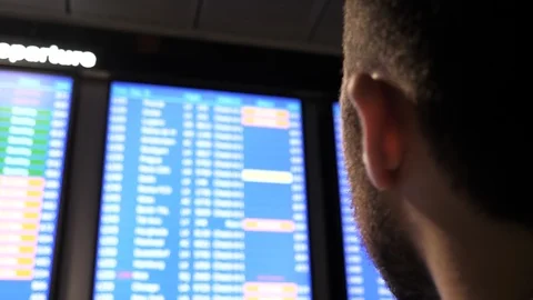 Young businessman looking at the board with flight schedule at the airport. Stock Footage 117260967
