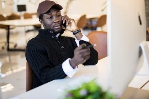 Young businessman looking at data on computer screen while making notes in no 写真素材