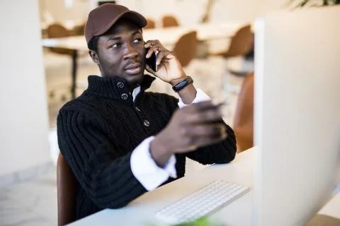 Young businessman looking at data on computer screen while making notes in no 写真素材