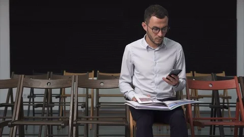 Young businessman looking at documents and holding a smartphone Stock Footage 77292446