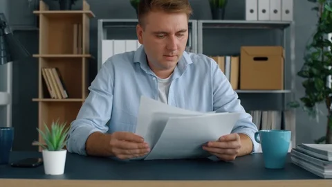 Young businessman looking at documents paper in modern office. Man working with  Stock Footage 116428344