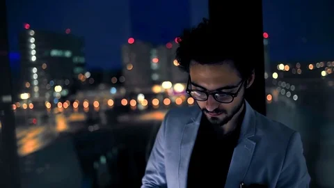 Young businessman looking at tablet by background of the night city. Slow motion Stock Footage 70591006