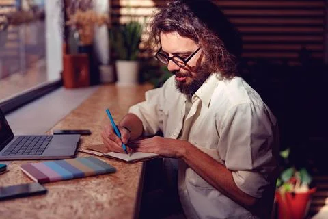 Young businessman making notes during working day at coworking space near window Stock Photos