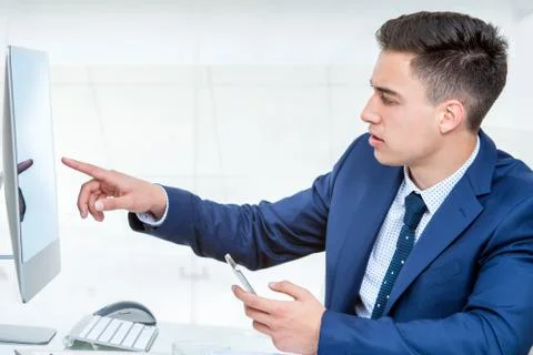 Young businessman pointing at blank computer screen. Stock Photos