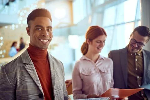 A young businessman is posing for a photo while standing in the hallway wit.. Stock Photos