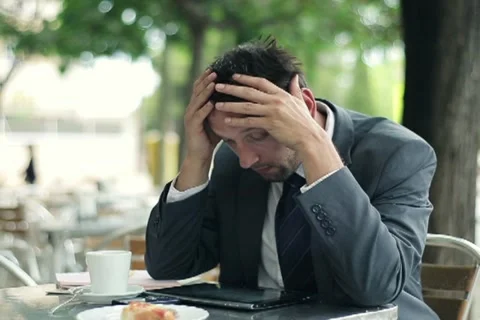 Young businessman reading bad news on tablet computer in cafe NTSC Stock Footage