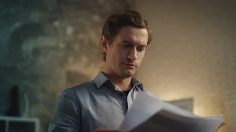 Young businessman reading documents in office, reviewing company statistics Stock Footage 340960977