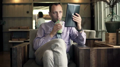 Young businessman reading something on tablet and drinking cocktail in  cafe HD Stock Footage 49617022