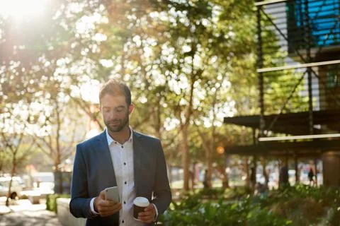 Young businessman reading a text while walking with a coffee Stock Photos