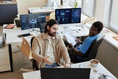 Young businessman showing data on computer screen to colleague Stockfoto's