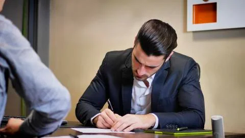 Young businessman signing document at desk in office Stock Photos