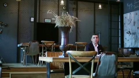 Young businessman sitting at the table in cafe, waiting waiter. Stock Footage 61215613
