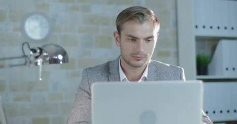 Young businessman in suit working while sitting at computer Stock Footage 81064318
