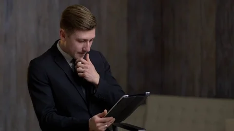 Young businessman with a tablet computer is engaged in business. A man is in a 스톡 동영상 71406568