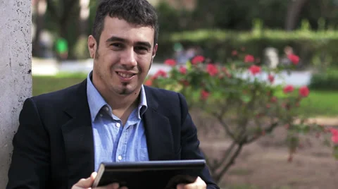 Young businessman with tablet computer in park looking at camera Stock-Footage 32942631