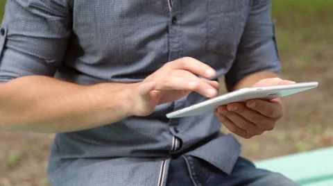 Young businessman with tablet computer sitting on bench in the park Stock Footage 67880728