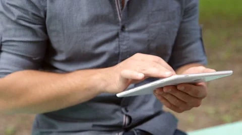 Young businessman with tablet computer sitting on bench in the park Stock Footage 67880807