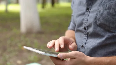 Young businessman with tablet computer sitting on bench in the park Stock Footage 67880838