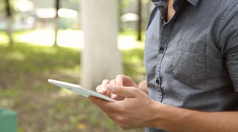Young businessman with tablet computer sitting on bench in the park Stock Footage 67880865