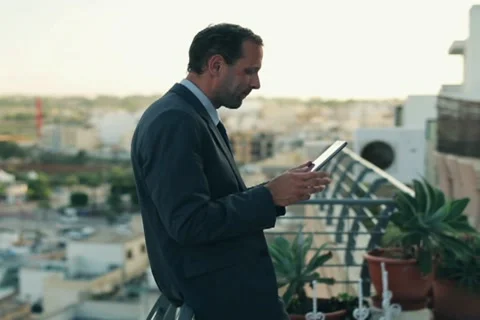 Young businessman with tablet computer standing on the terrace, crane shot Stock Footage