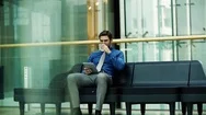 A Young Businessman With Tablet Sitting On A Bench In A Modern Building. Stock Footage