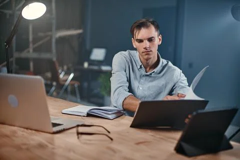 Young businessman taking notes in a notebook in a night office. Stock Photos
