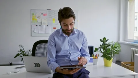 Young businessman talking through wireless headphones while using tablet in o 動画素材 109351861