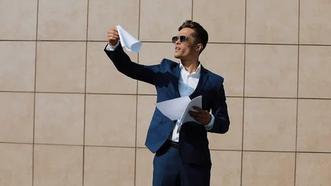 Young businessman throws up documents and funny dancing near office building Stock Footage 90897663