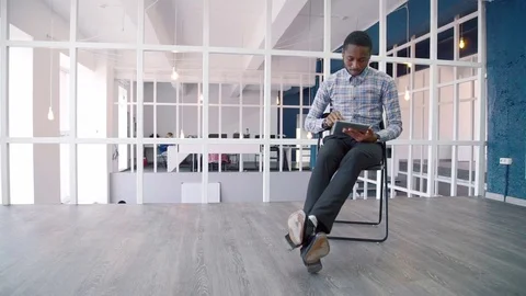 Young businessman uses tablet while sitting in leading company. Stock Footage 82354911