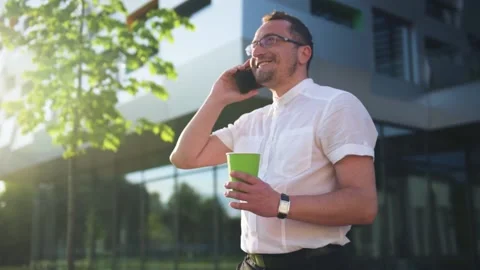 Young businessman using cellphone while walking near office. Stock Footage 156189511