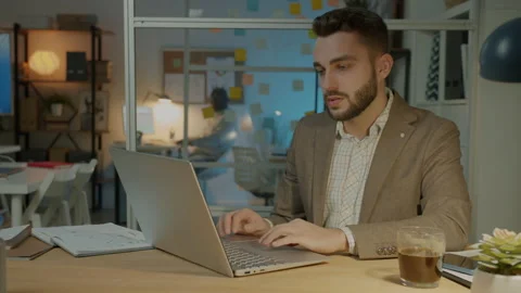Young businessman using computer in dark office concentrated on work Stock Footage 204708281