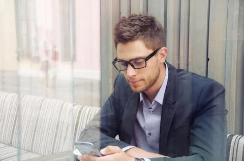 Young businessman using device and drinking coffee in the city cafe Stock Photos