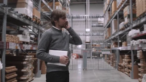 Young Businessman Using Digital Tablet And Mobile Phone In Warehouse Video stock 72030596