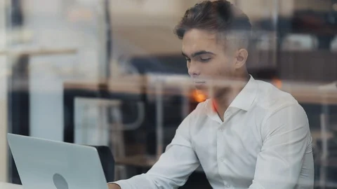 Young businessman using laptop computer at cozy coffee shop. Window Reflection Video stock 126538357