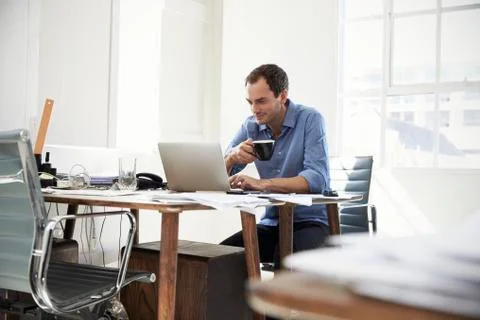 Young businessman using laptop computer and drinking coffee Stock Photos