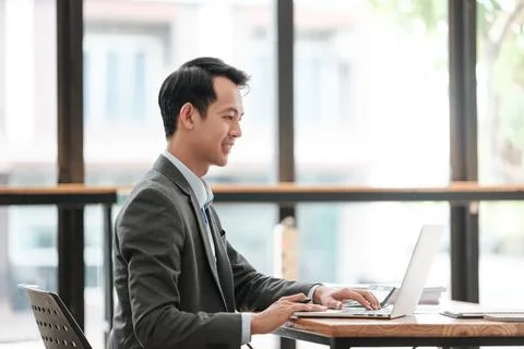 Young Businessman Using Laptop Computer in Modern Office. Manager Thinks About Stock Photos
