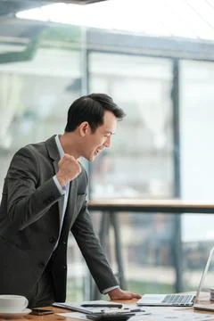 Young Businessman Using Laptop Computer in Modern Office. Manager Thinks About Stock Photos