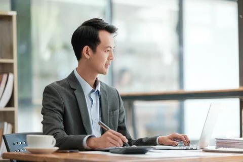 Young Businessman Using Laptop Computer in Modern Office. Manager Thinks About Stock Photos