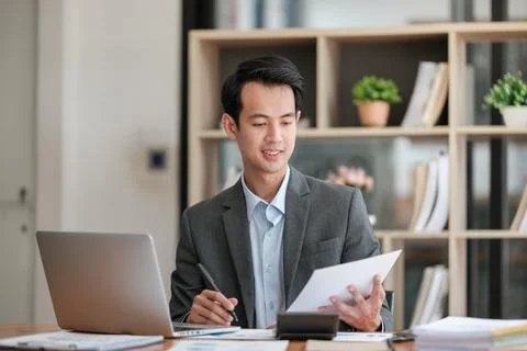 Young Businessman Using Laptop Computer in Modern Office. Manager Thinks About Stock Photos