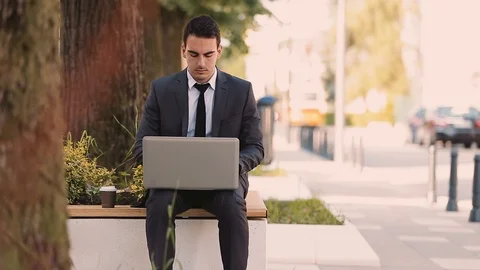 Young Businessman Using Laptop While Sitting At Bench Stock Footage 87405353