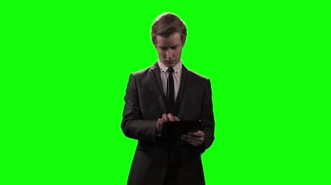 Young businessman using mobile device / tablet computer against green screen Video stock 49547817