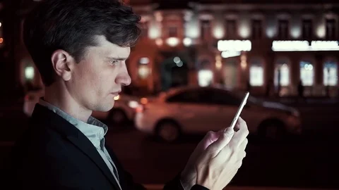 Young businessman using smartphone on a busy urban street at night Stock Footage 80009683