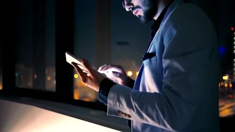 Young businessman using tablet by background of the night city. Side view. Slow  Stock Footage 70590633