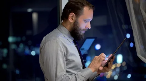 Young businessman using tablet computer by window in office at night Stock Footage 56936154