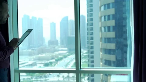 Young businessman using tablet computer standing by window at home Stock Footage 69990063
