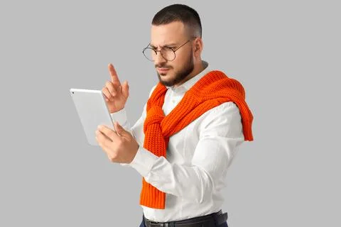 Young businessman using tablet computer on light background. Search concept Stock Photos